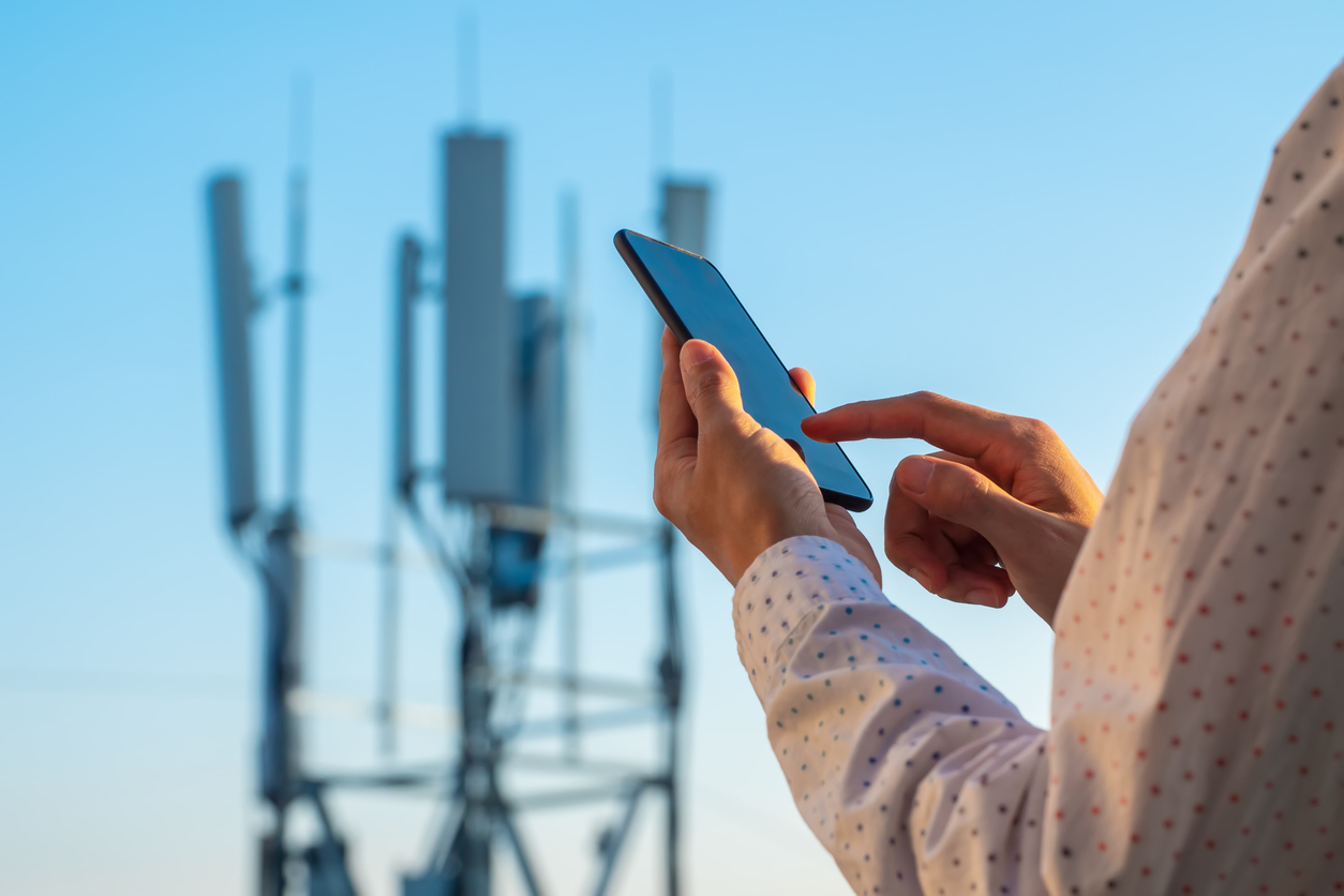 Person using mobile phone with cell tower in background