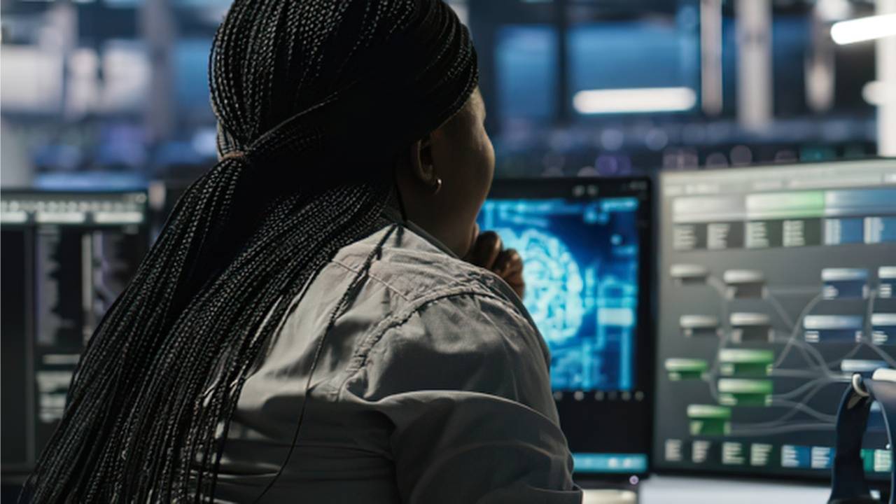 A command center operator sitting at ergonomic operator consoles monitoring real-time network data visualization streams and system topology maps.